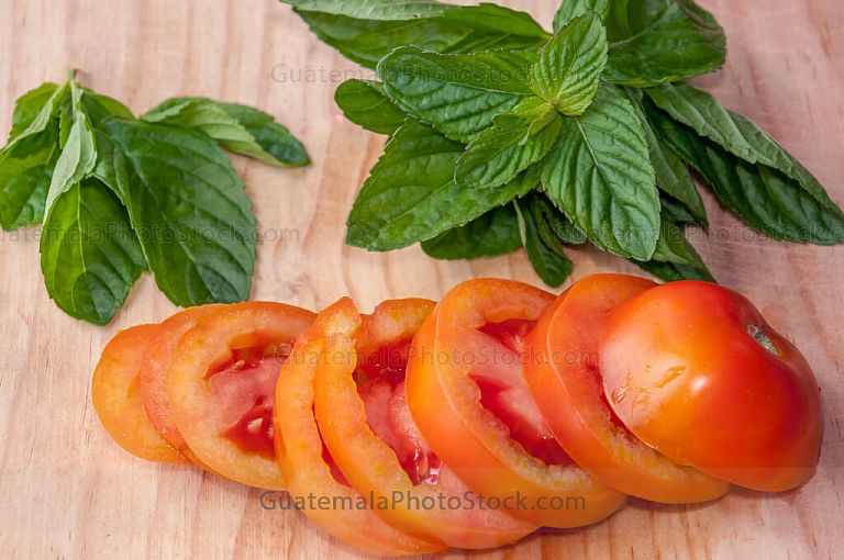 Hierba buena y tomate sobre tabla de picar