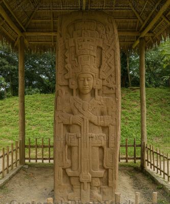 Estela maya bajo palapa en claro tropical de Quiriguá