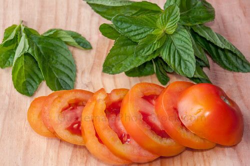Hierba buena y tomate sobre tabla de picar