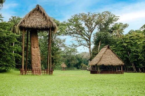Estela maya bajo palapa en claro tropical de Quiriguá